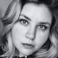 A black-and-white headshot image of writer JK Murphy. Murphy is looking into the camera and tilting her head to the side.