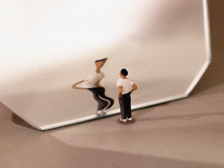 a figurine looking at a distorted reflection in the mirror to represent body dysmorphia