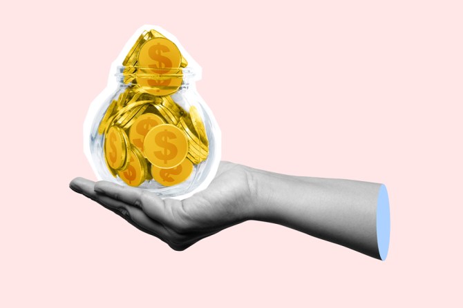 A hand holding a jar of cash. This person may need to see a financial therapist